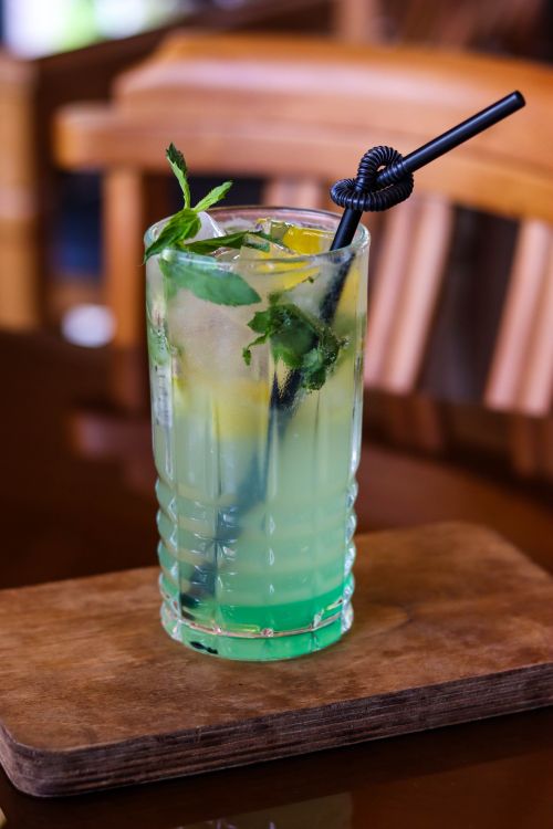 Free Colorful lemon mint iced drink with black straw on a wooden surface indoors. Stock Photo