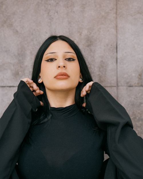 Free Portrait of a stylish woman posing in a fashionable outfit against a concrete wall in Buenos Aires. Stock Photo