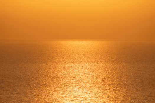A breathtaking golden sunset over a calm sea in Greece, capturing the shimmering water and peaceful horizon.