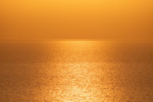 Free A breathtaking golden sunset over a calm sea in Greece, capturing the shimmering water and peaceful horizon. Stock Photo