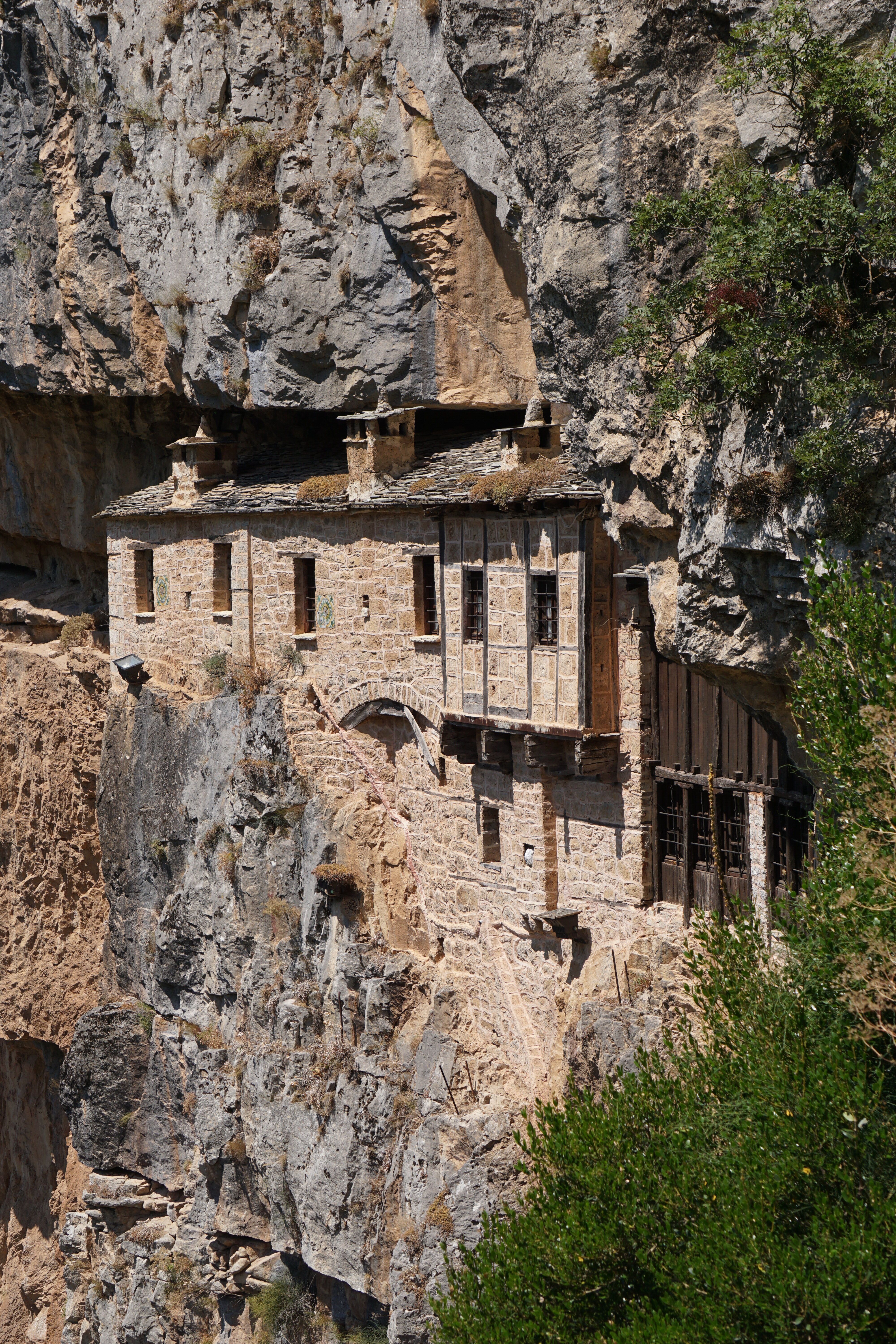 A breathtaking view of a monastery built into the rocky cliffs of Greece, showcasing architectural marvel.