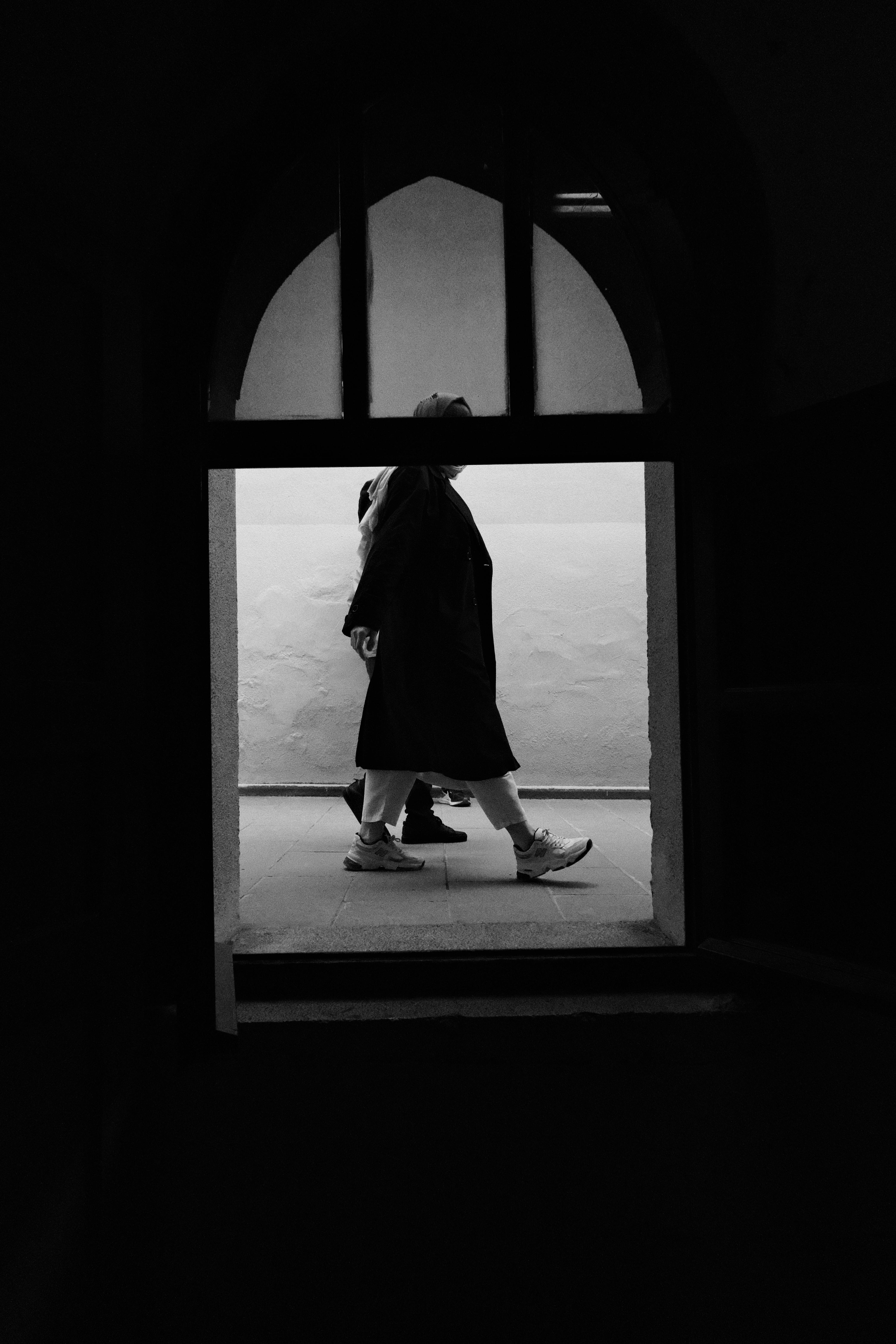 Black and white photo of people walking in an archway in Ankara, Türkiye, capturing contrast and movement.