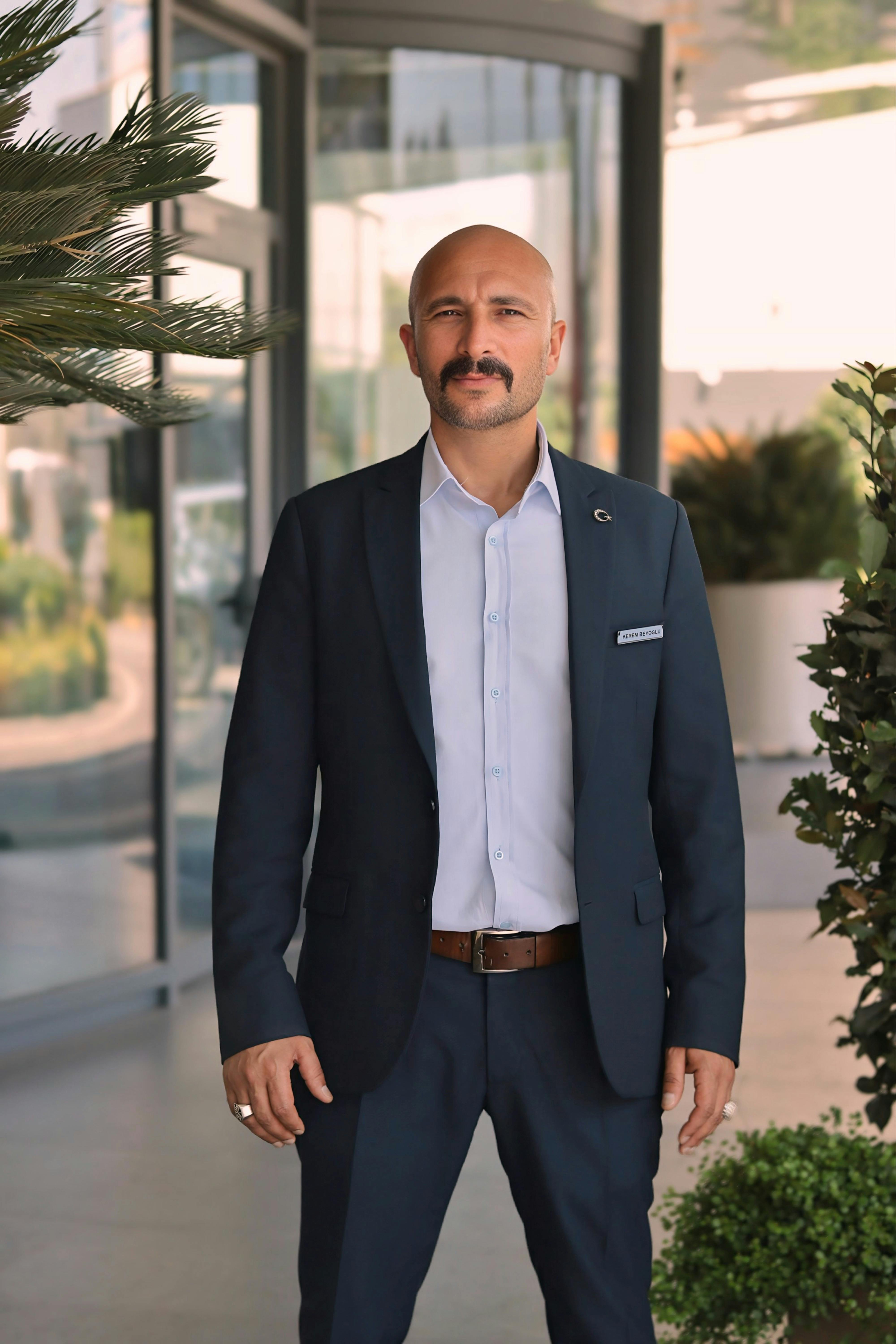 Confident businessman in a suit standing in front of a modern building entrance. Professional and polished look.