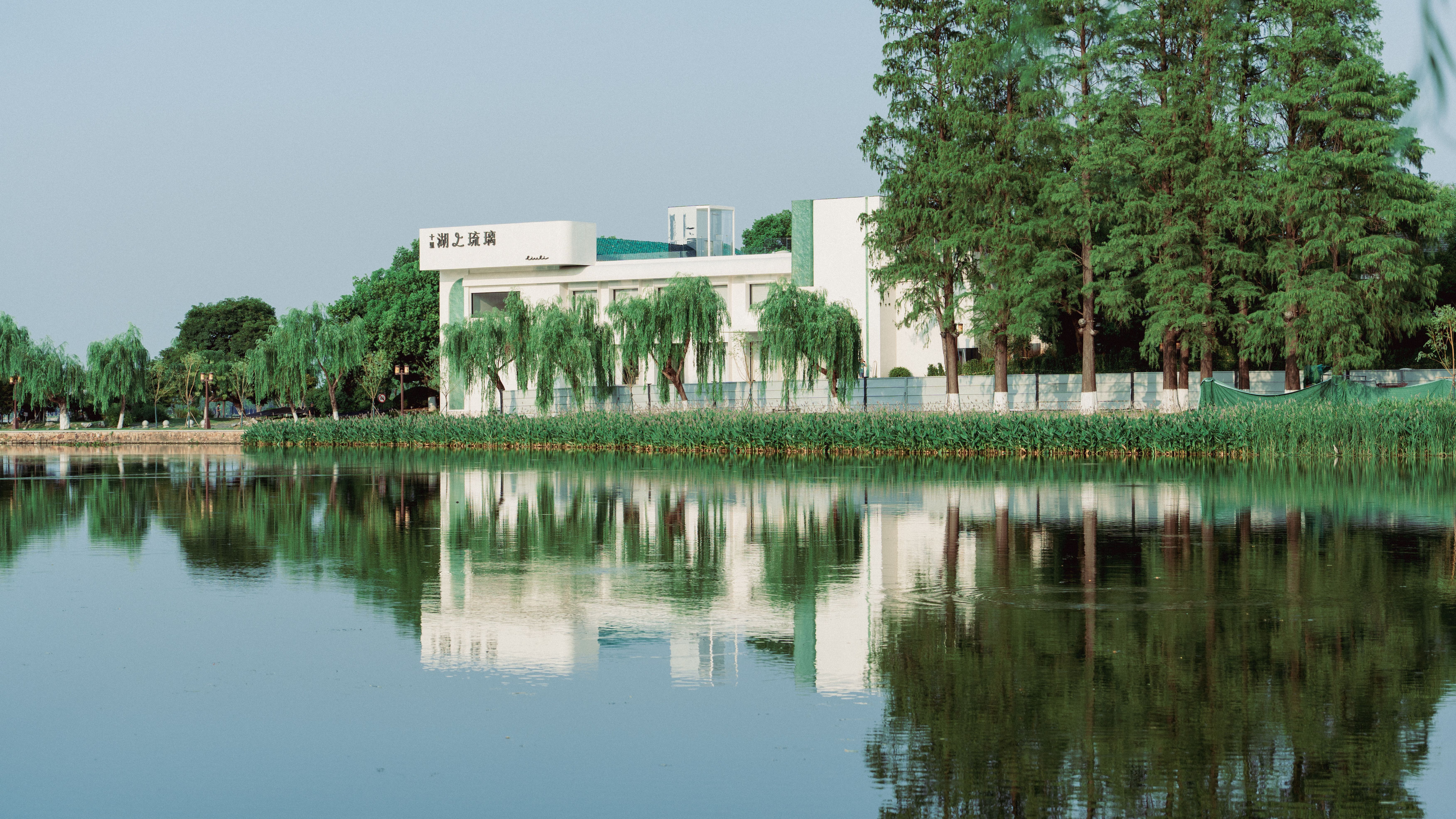 A modern building surrounded by trees, reflecting in a calm lake, creating a serene and picturesque landscape.
