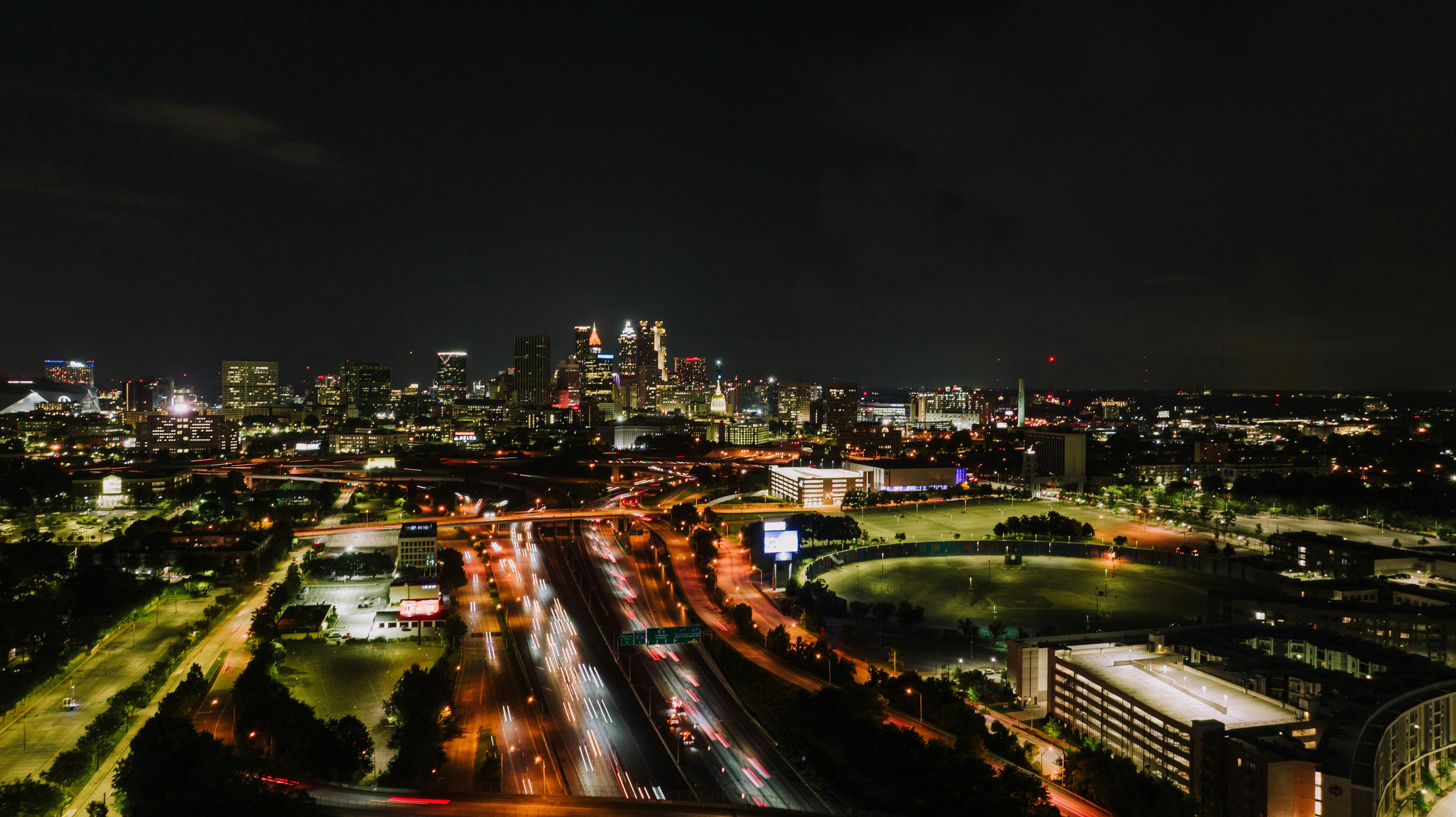 Aerial view of Atlanta city skyline at night with vibrant light trails on highway.