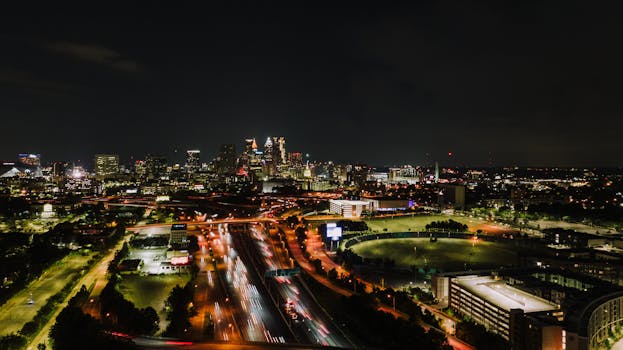 Aerial view of Atlanta city skyline at night with vibrant light trails on highway.