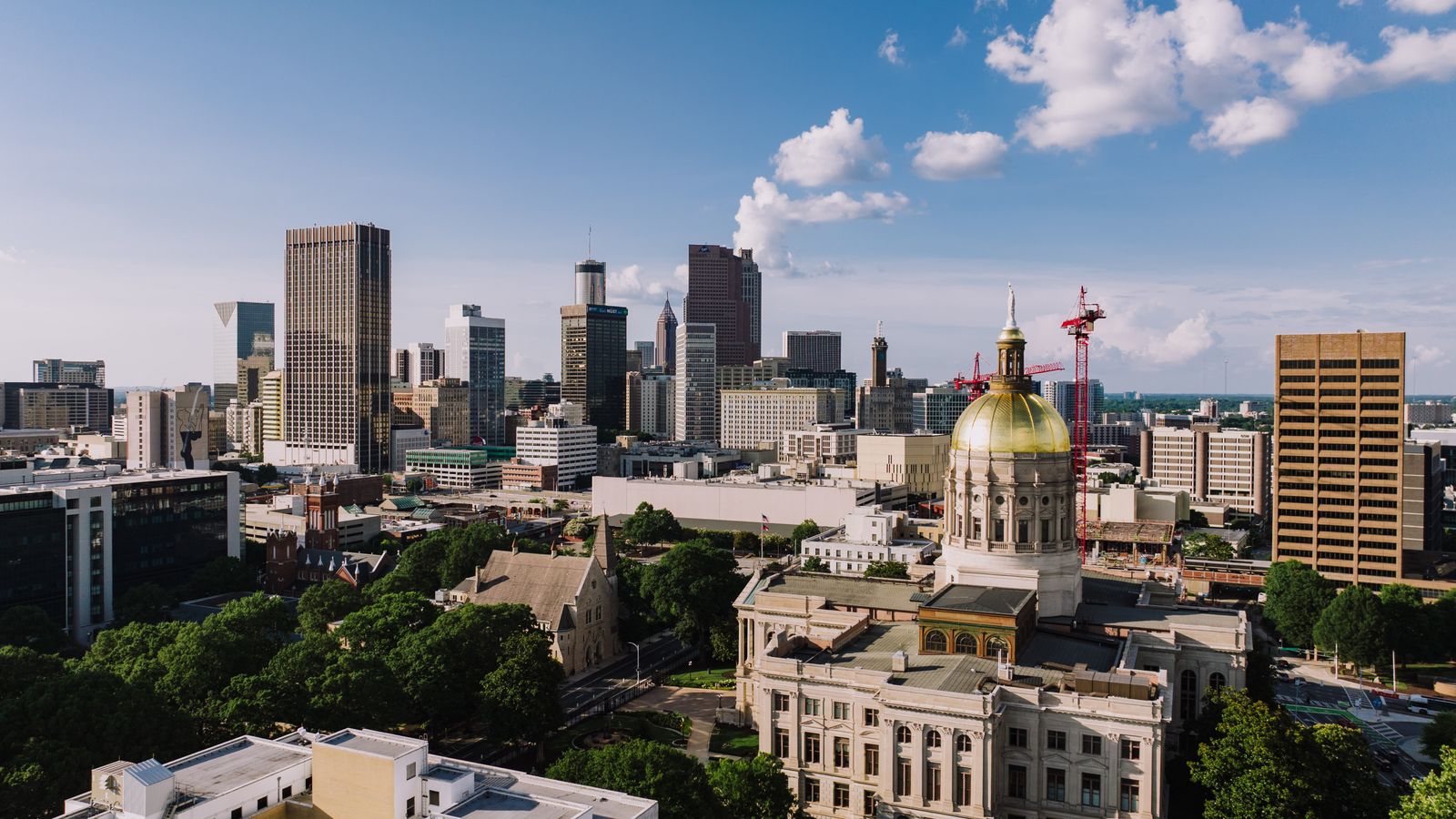 A breathtaking aerial view capturing the Atlanta skyline and the Georgia State Capitol under a clear blue sky.