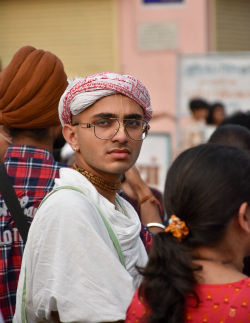 Free Young man wears traditional attire and headwear amid a diverse crowd outdoors. Stock Photo