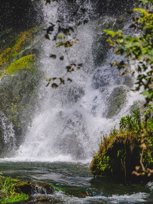 Free A peaceful waterfall cascading through vibrant greenery in a tranquil forest environment. Stock Photo