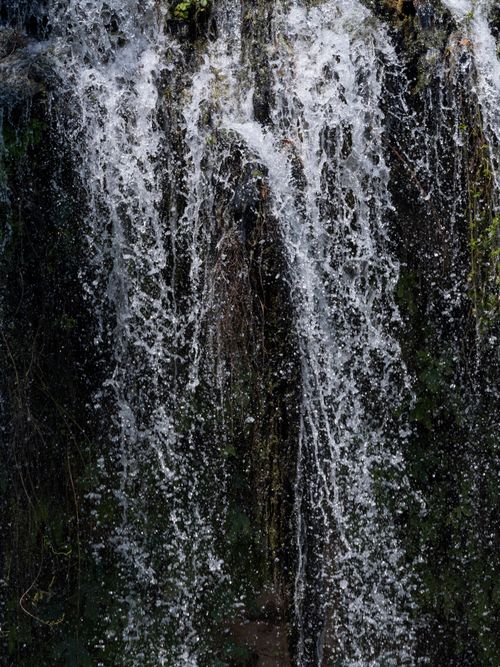 Free A peaceful waterfall flows over rocks in a lush outdoor setting, creating a tranquil scene. Stock Photo