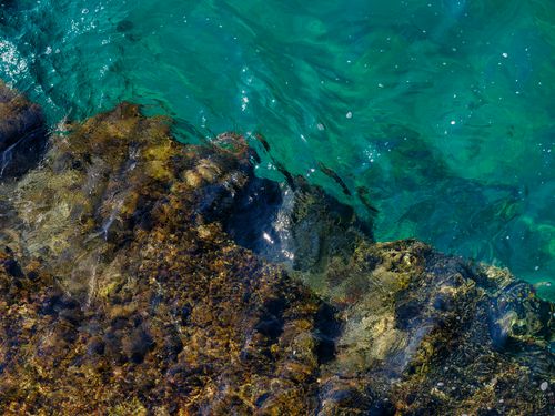 Free A scenic view of vibrant blue ocean water meeting the rugged coastal rock formations, capturing a moment of natural tranquility. Stock Photo