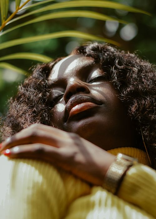 Free Close-up of a woman basking in sunlight with greenery in the background. Stock Photo