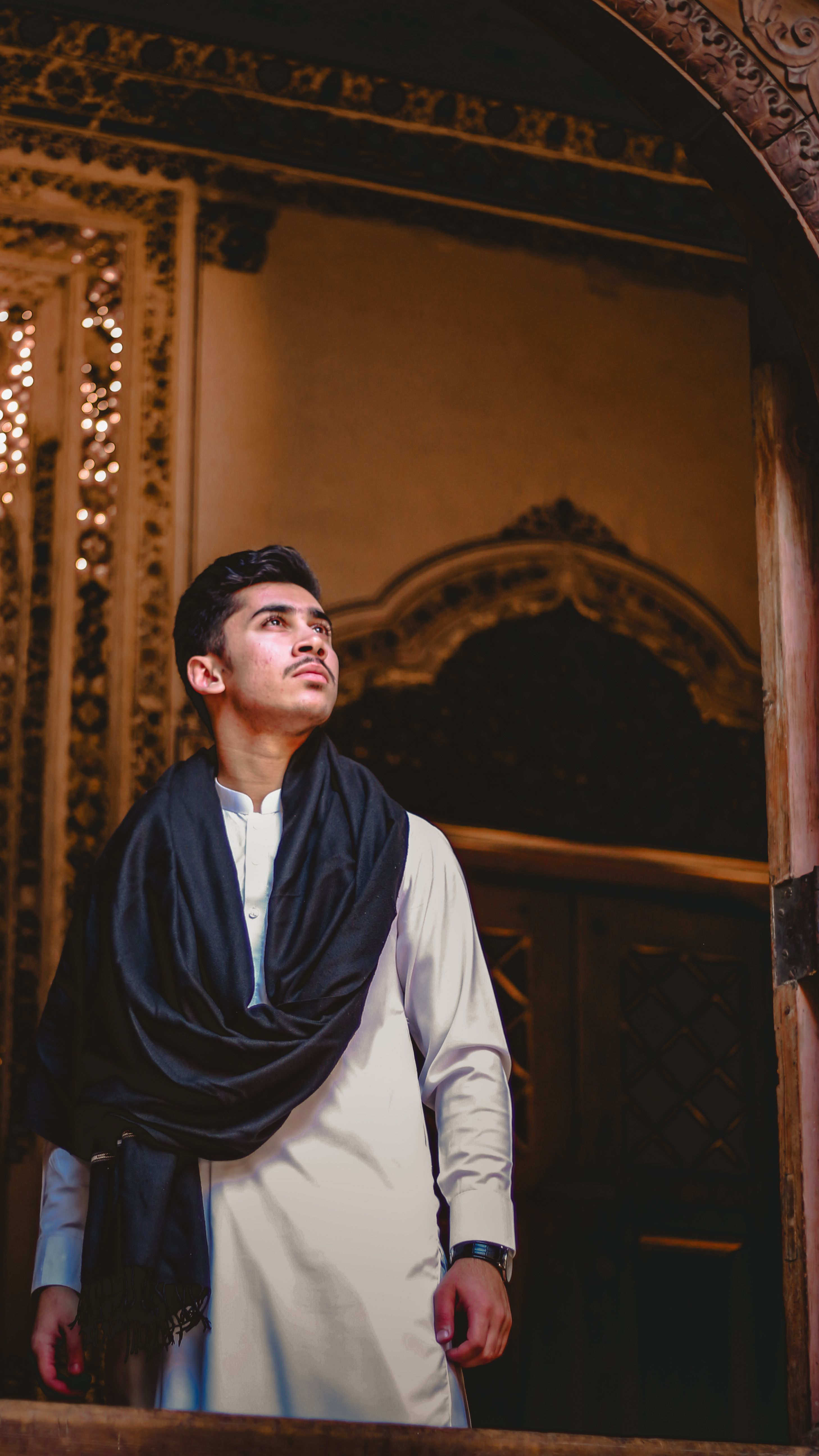 An adult male in traditional clothing poses elegantly inside historic architecture in Peshawar, Pakistan.
