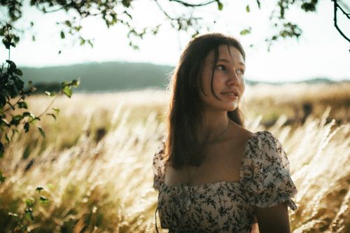 Free A contemplative young woman in a field of dry grass during golden hour in Ukraine, capturing natural beauty and moody aesthetics. Stock Photo