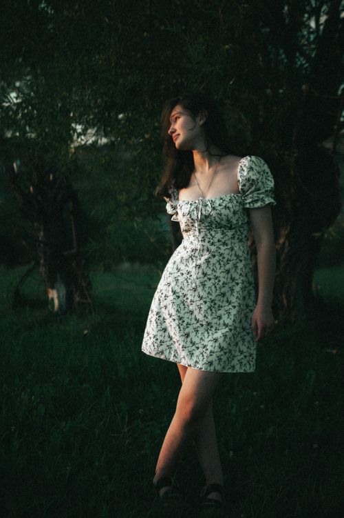 Free A woman in a floral dress stands in the moody evening light outdoors in Ukraine. Stock Photo