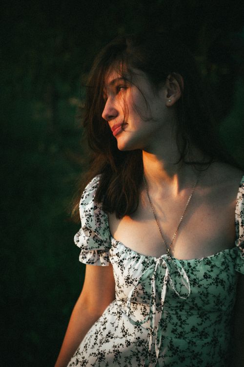 Free Young woman in a white floral dress enjoying a peaceful sunset outdoors, capturing natural beauty. Stock Photo