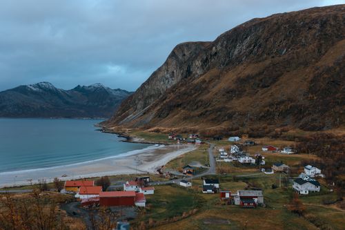 Free A picturesque Norwegian village by a beach and mountains in autumn light. Stock Photo