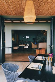 Stylish indoor-outdoor dining space with modern decor and cozy seating arrangement.