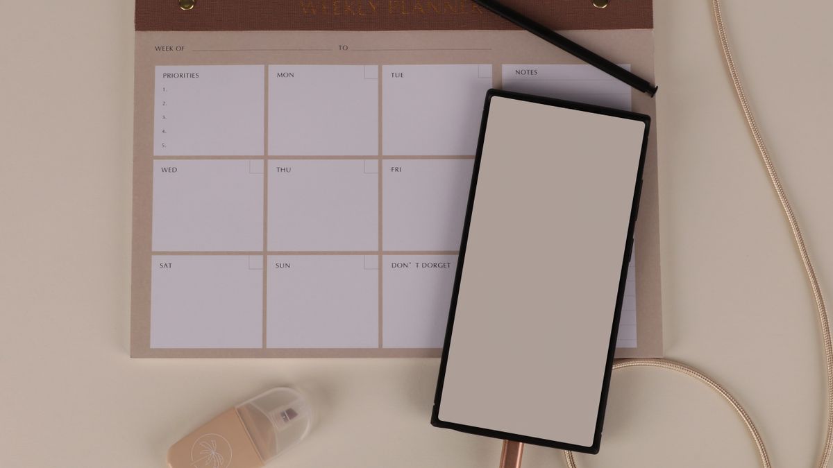 Modern desk setup with a weekly planner, notebook, and phone