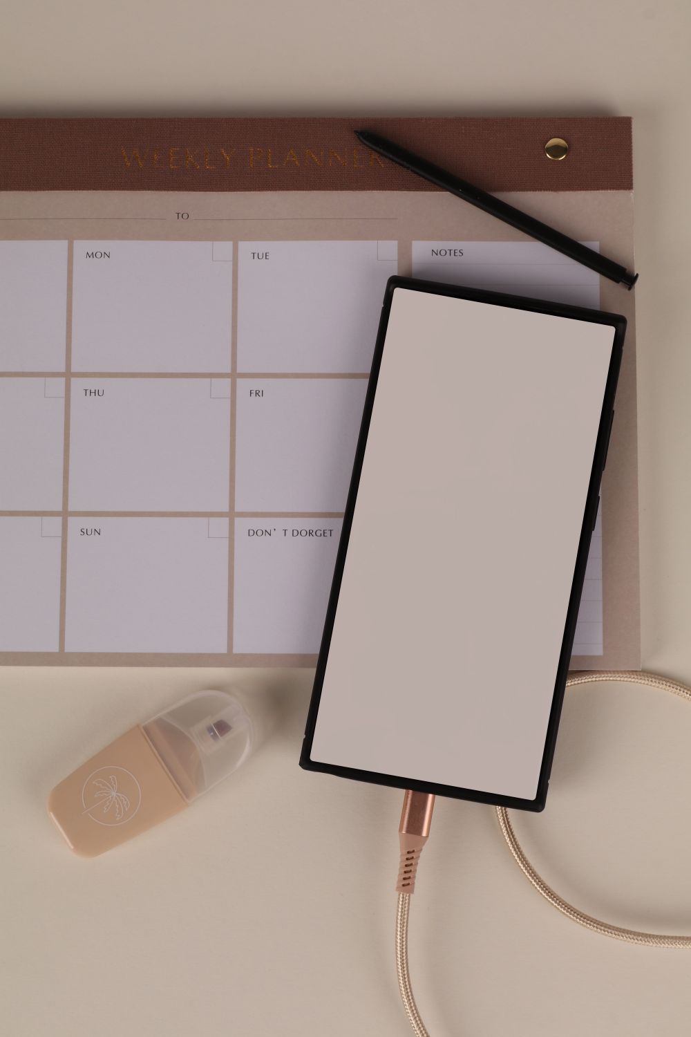 Wochenplaner und Smartphone nebeneinander auf einem hellen Schreibtisch