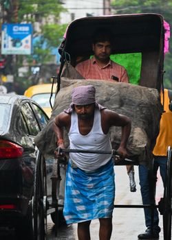 A manual rickshaw puller navigates a crowded urban street with a passenger, showcasing traditional transport.