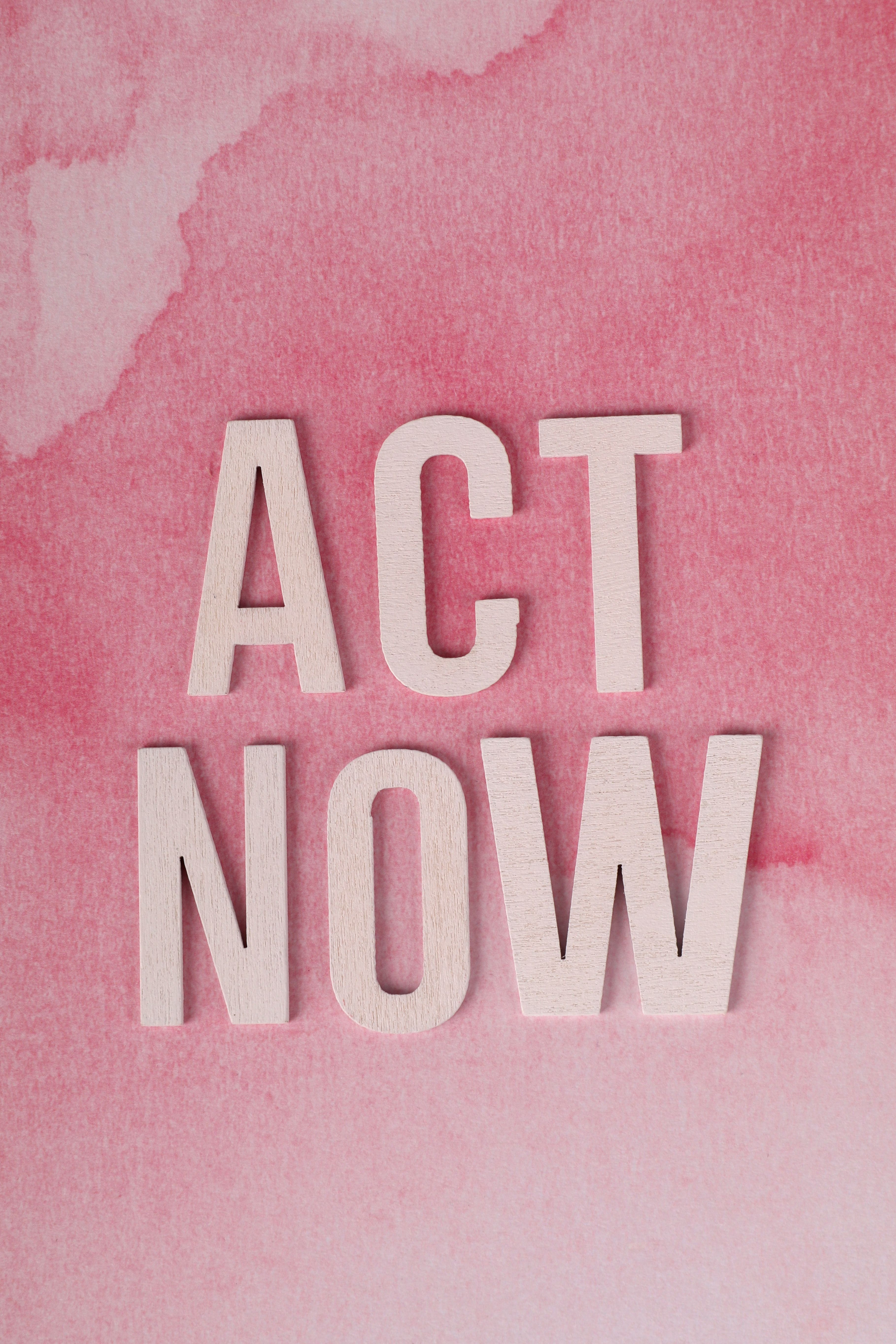 Motivational text "Act Now" on a pink watercolor backdrop, encouraging immediate action.