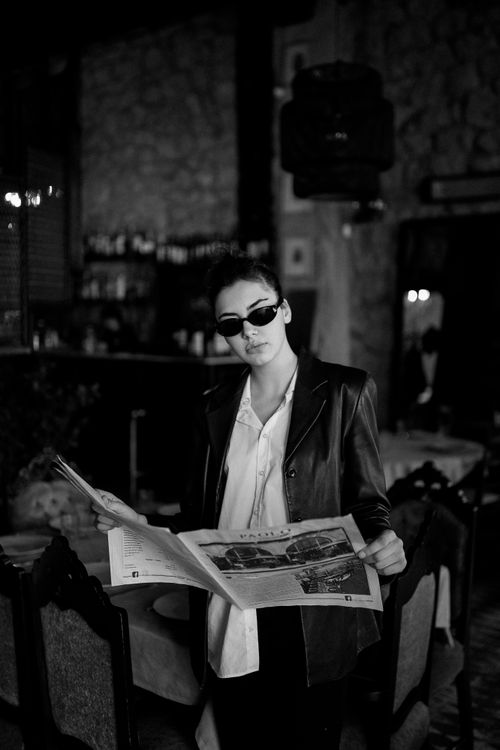 Free Stylish woman in sunglasses reading a magazine in a moody Georgian café. Stock Photo