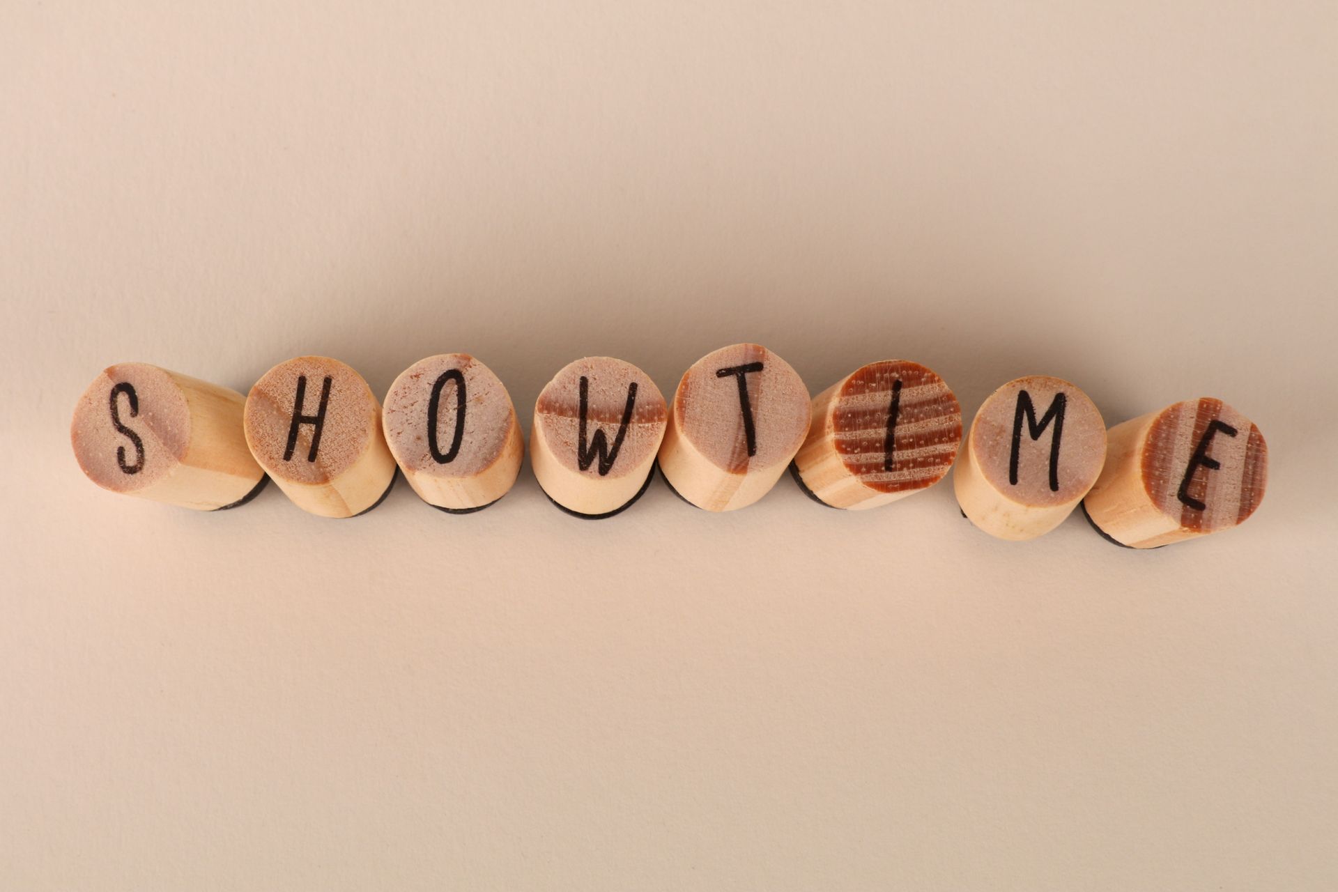 Image of wooden stamps spelling 'Showtime', arranged neatly on a beige background.