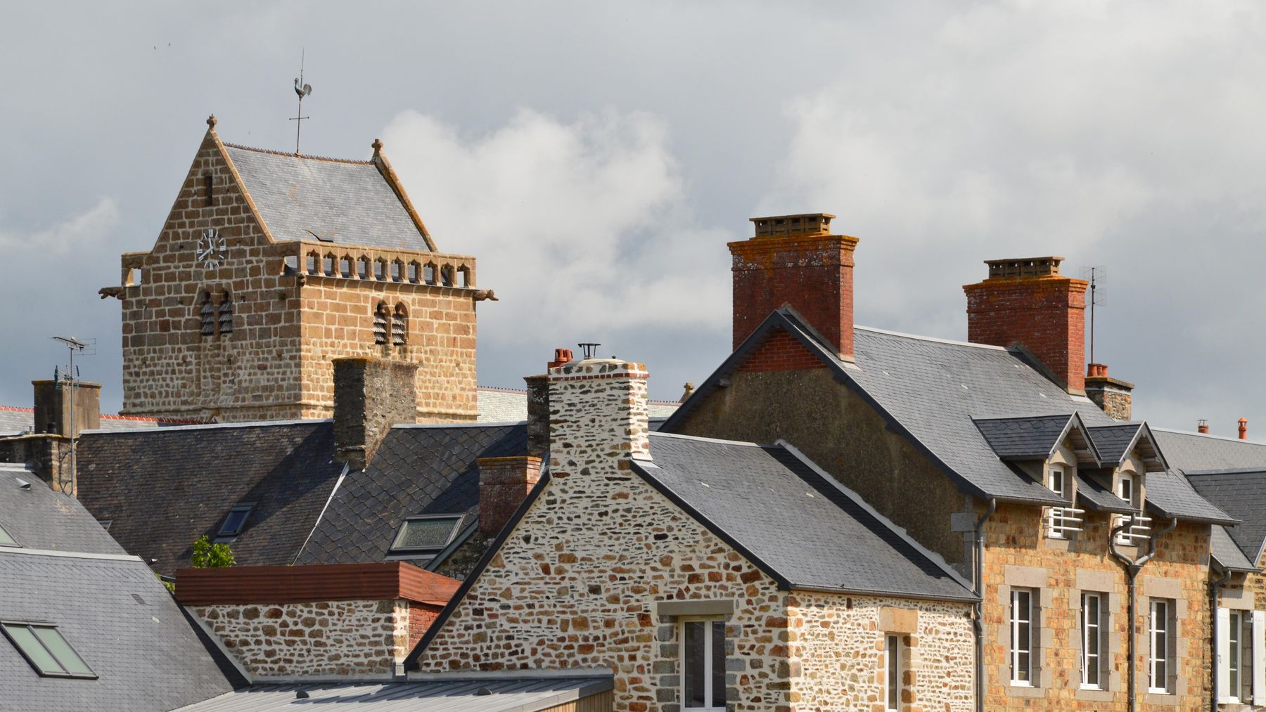 Historic slate rooftops and a stone church tower above an old town — photo by SlimMars 13 on Pexels