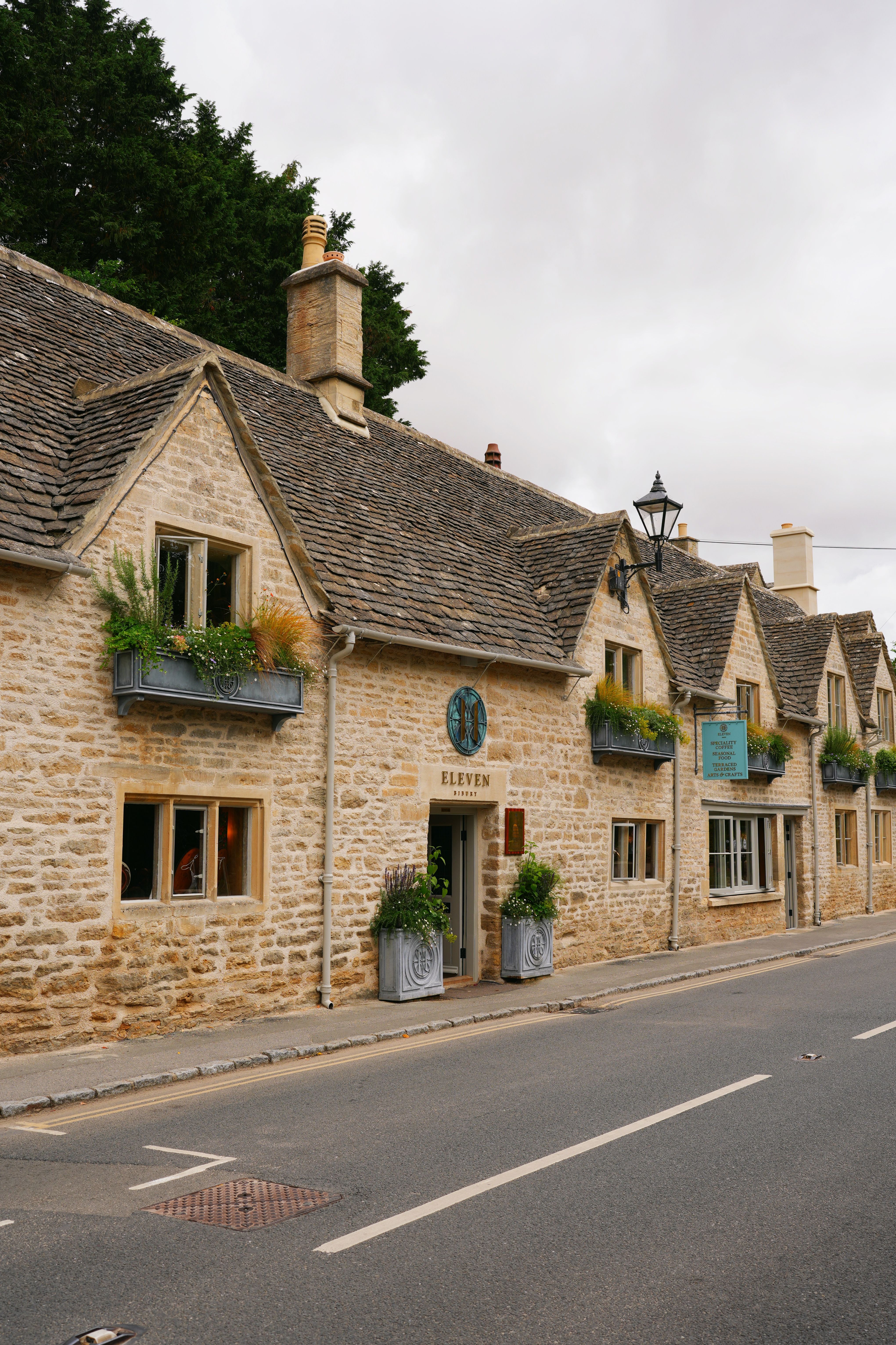 Quaint stone houses with floral displays in a picturesque Cotswolds village.