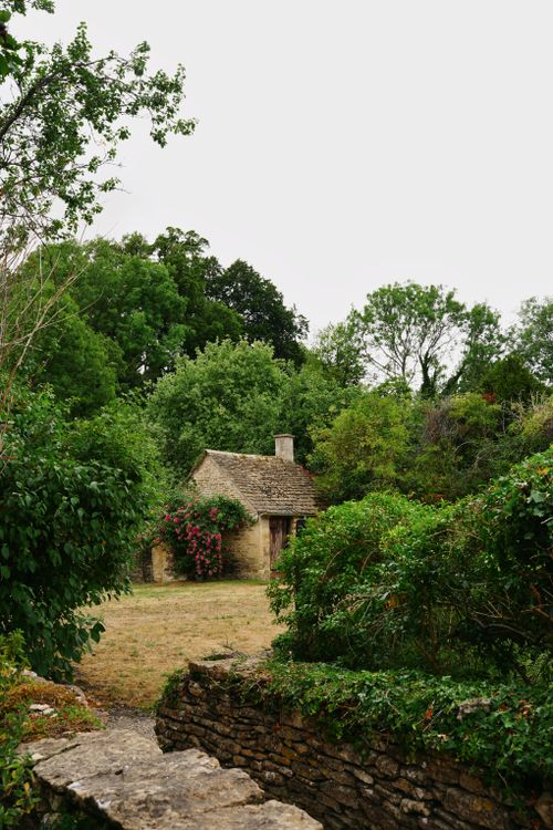 Free Idyllic stone cottage surrounded by lush greenery in an English rural setting. Stock Photo