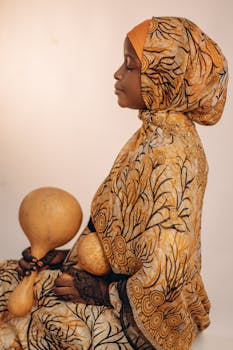 Portrait of a woman in traditional African clothing holding gourds, against a neutral background.