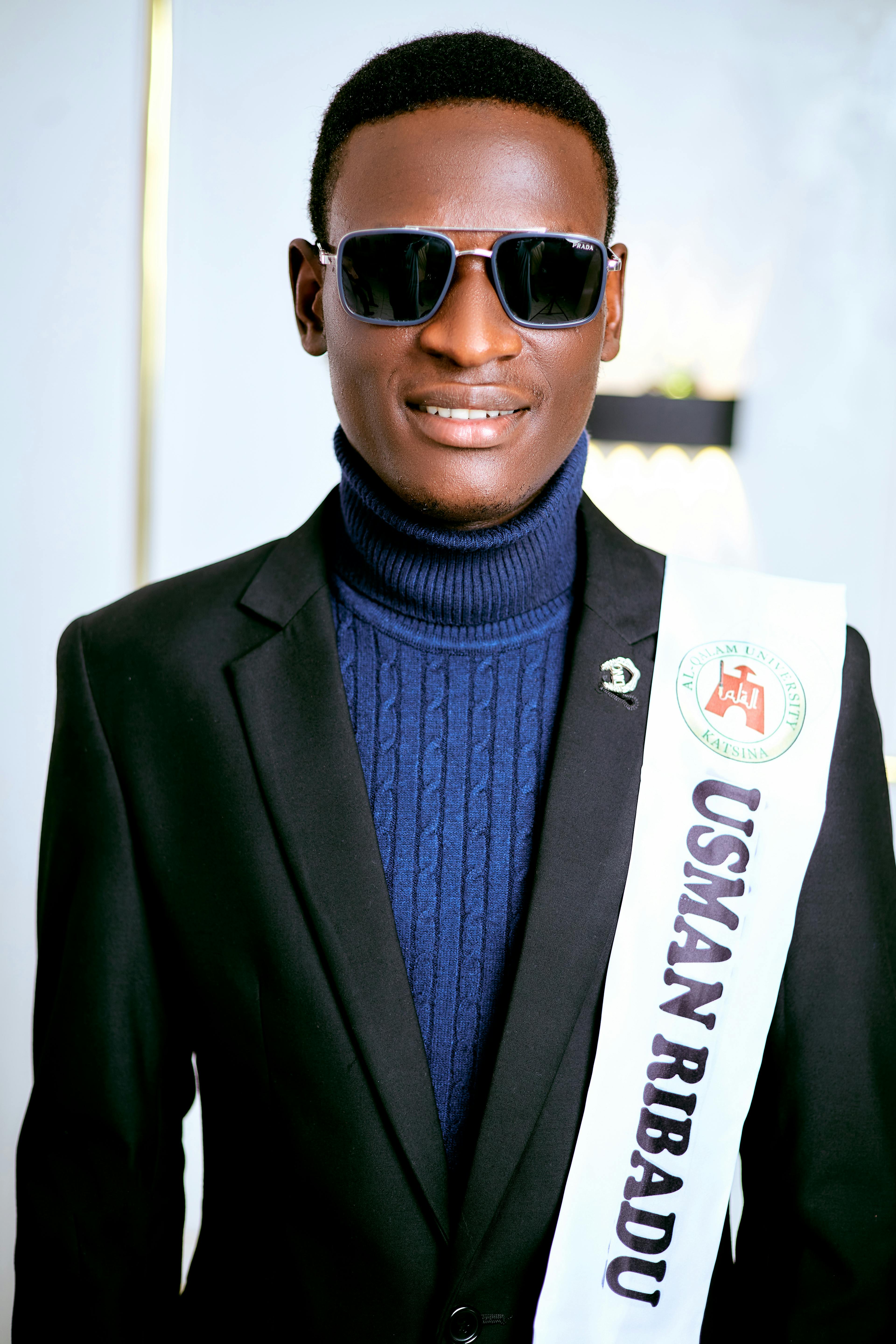 Stylish man wearing shades and a suit indoors, exuding confidence.