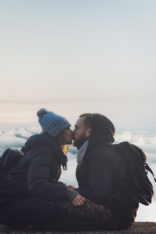 Free Man and Woman Kissing Near Sea of Clouds Stock Photo