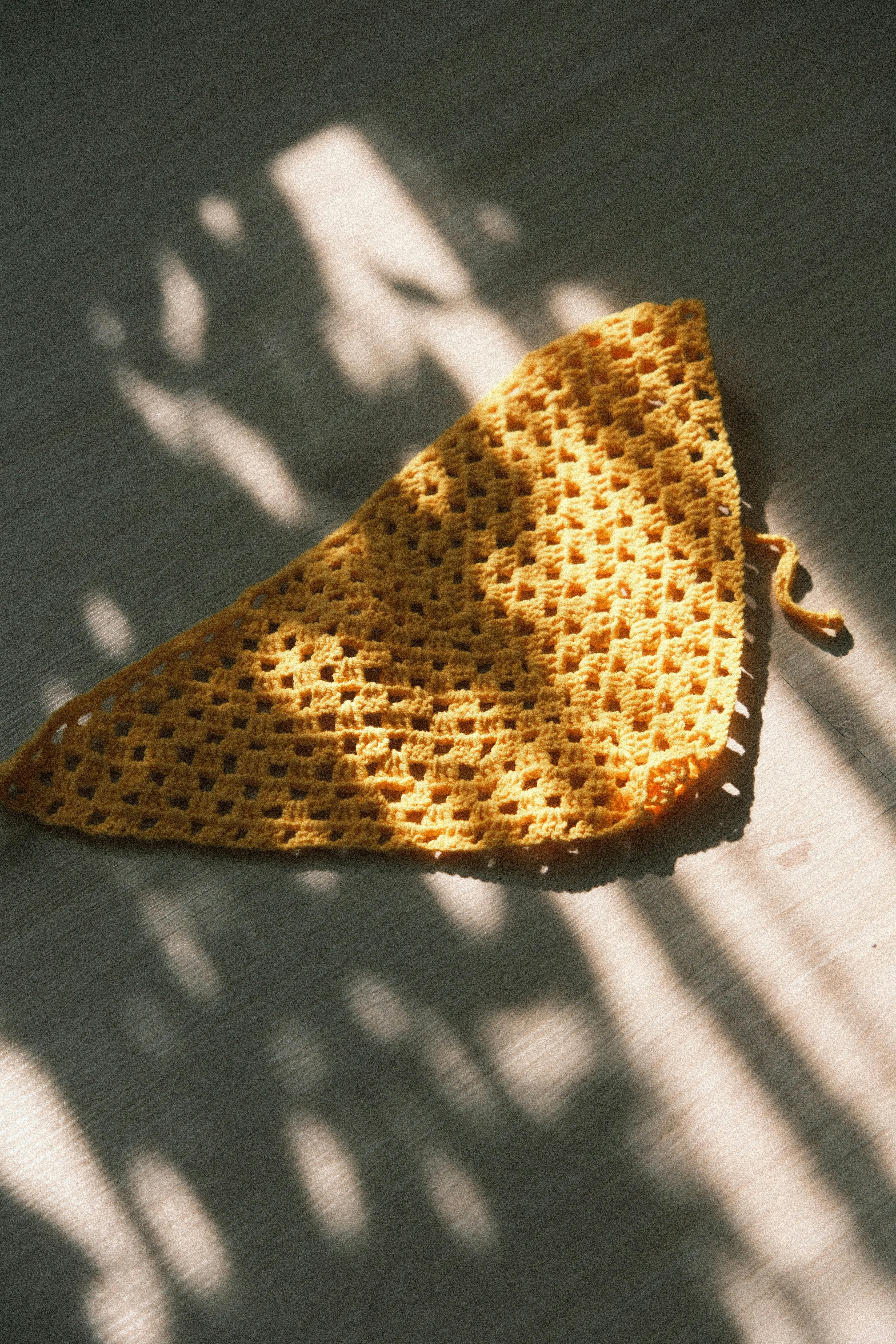 Gratis Una tela de crochet de color amarillo vibrante iluminada por la luz del sol, proyectando sombras artísticas. Foto de stock