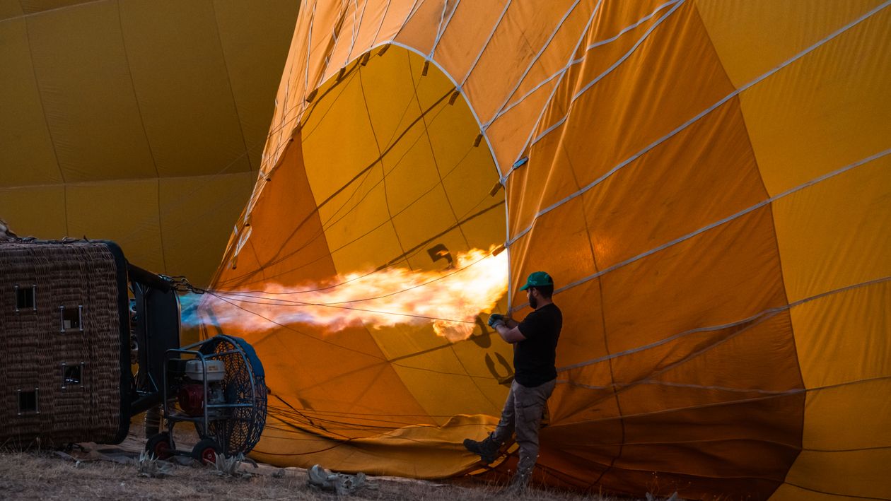 Imageman Inflating Ballon Man Inflating Hot Air Balloon with Flame Outdoors · Free Stock Photo