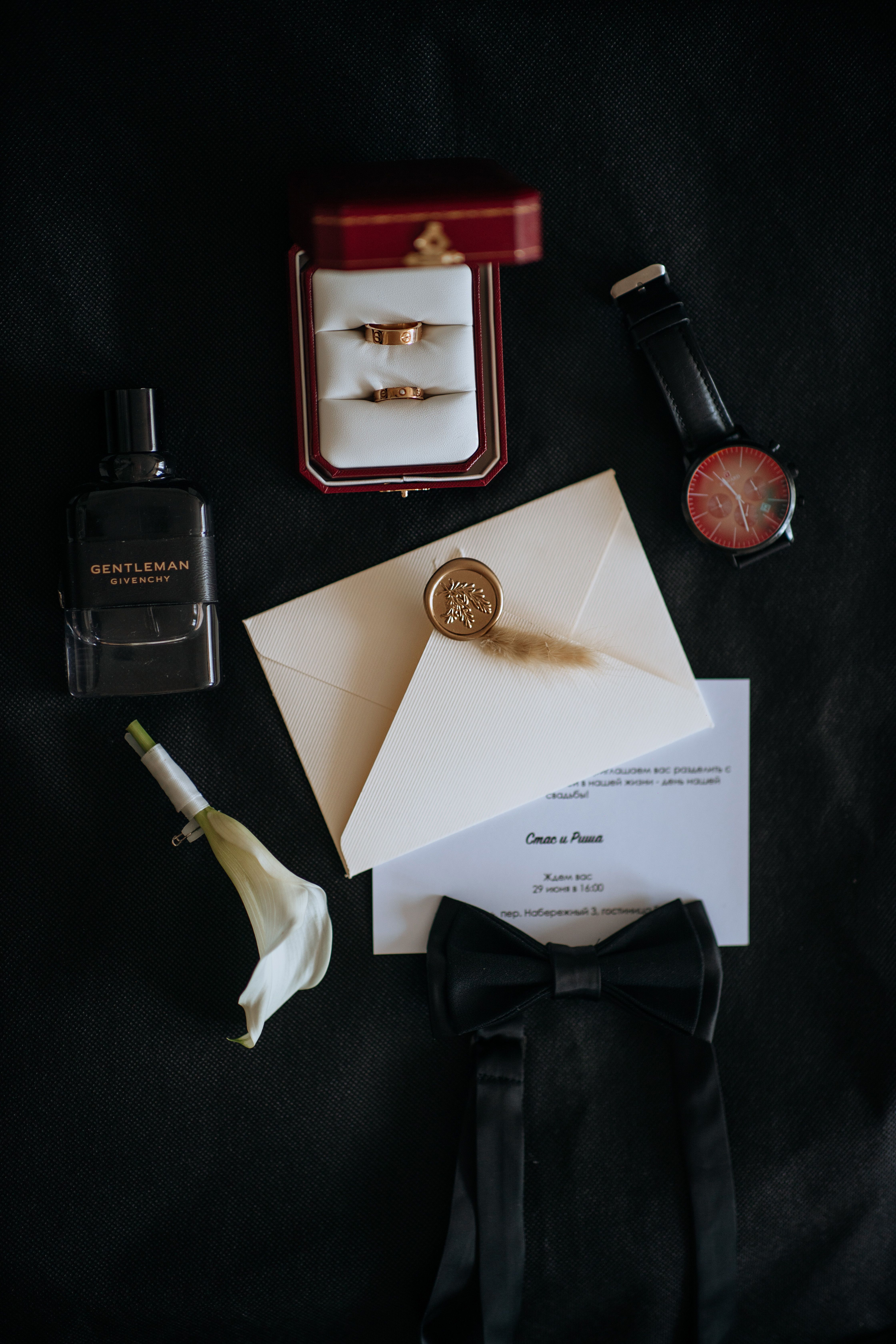 Sophisticated wedding accessories and rings arranged elegantly on black surface.
