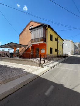 A vibrant house on a quiet street under clear blue skies, featuring a modern design.