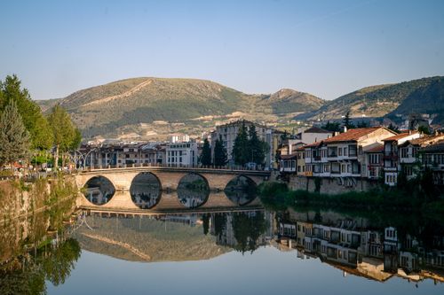 Free A scenic view of a historic Ottoman bridge over a river with mountain backdrop. Stock Photo
