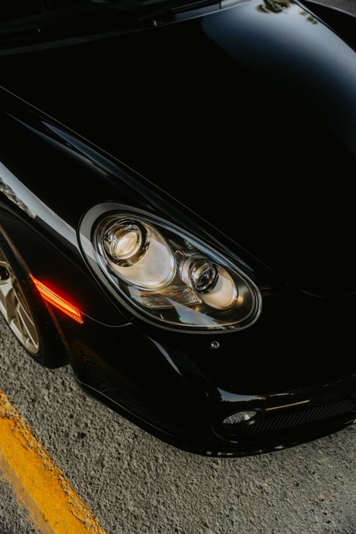 Free Close-up of a black sports car's headlight, vibrant urban setting. Stock Photo
