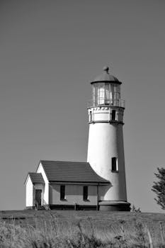 A serene black and white photograph of a classic lighthouse on a clear day in Oregon, USA.