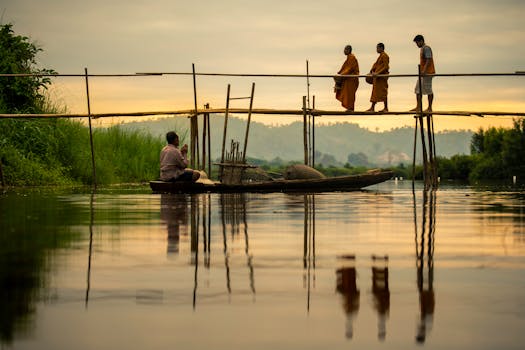 在泰国日出时分，僧侣们穿过木桥，河流平静，场景宁静