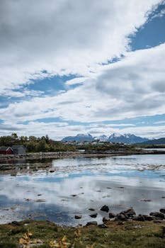 Beautiful view of a Norwegian fjord with snow-capped mountains and reflecting blue skies.