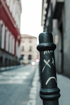 Urban street scene in Madrid featuring graffiti on metal pole with blurred architectural background.