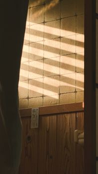 Warm sunlight casts patterned shadows through a traditional Japanese interior doorway.