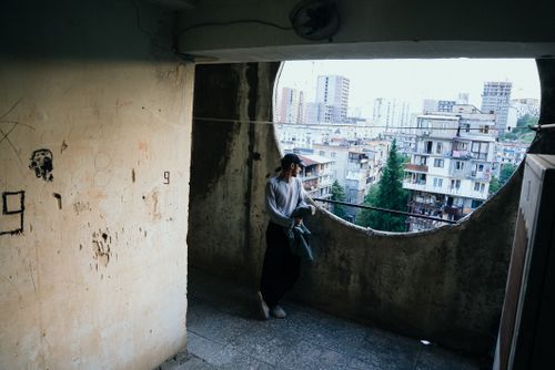 Free A person stands on a rustic balcony overlooking T'bilisi, Georgia's cityscape. Stock Photo