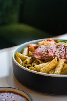 Savor a mouthwatering steak served with pesto pasta, perfect for meat lovers and Italian food enthusiasts.