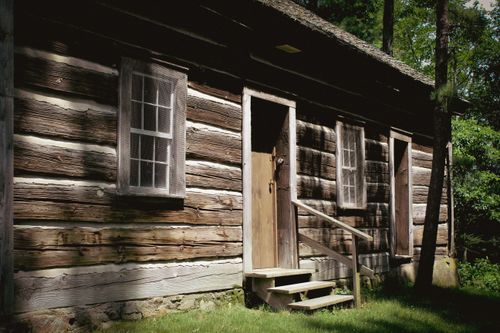 Free Charming rustic wooden cabin in a serene forest setting, bathed in natural daylight. Stock Photo