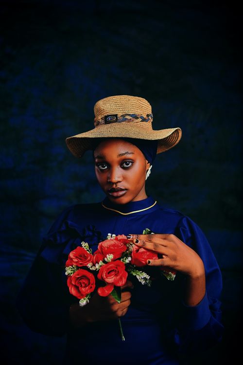 Free A woman in a straw hat holding red roses against a dark background. Stock Photo