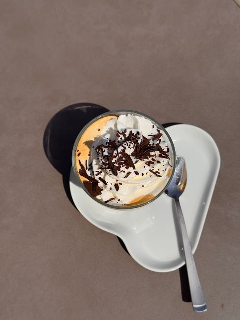 A tall glass of iced coffee with a swirl of pale vanilla sweet cream layered over dark cold brew concentrate, ice cubes visible through the glass, condensation beading on the outside.
